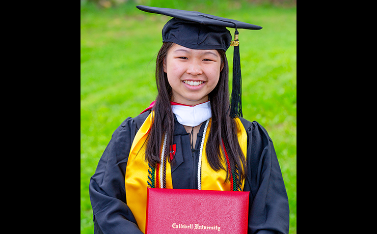 Michelle Eng standing and smiling with her Bachelor of Arts degree in biology.