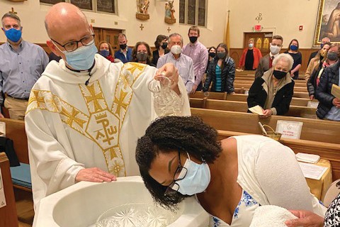 Student De-Jane Grant being baptized by Msgr. Robert Emery, pastor of St. Aloysius, during the Easter Vigil.